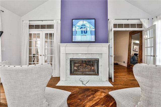 living room featuring wood finished floors, high vaulted ceiling, french doors, and a premium fireplace