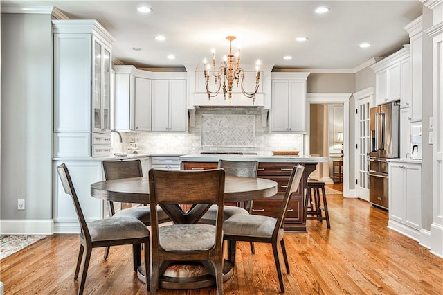 kitchen with light wood-style flooring, light countertops, crown molding, a notable chandelier, and high quality fridge