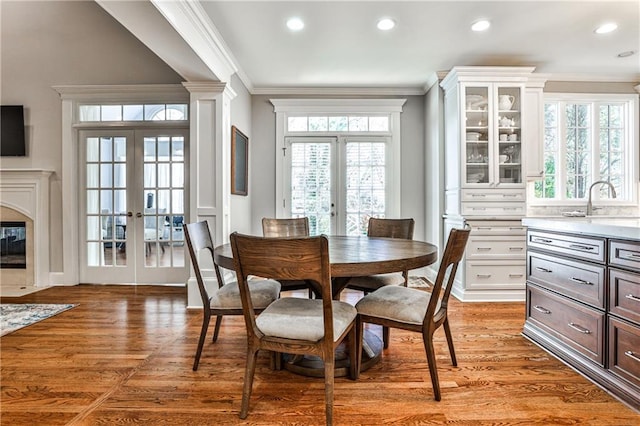 dining area with french doors, light wood-type flooring, and ornamental molding