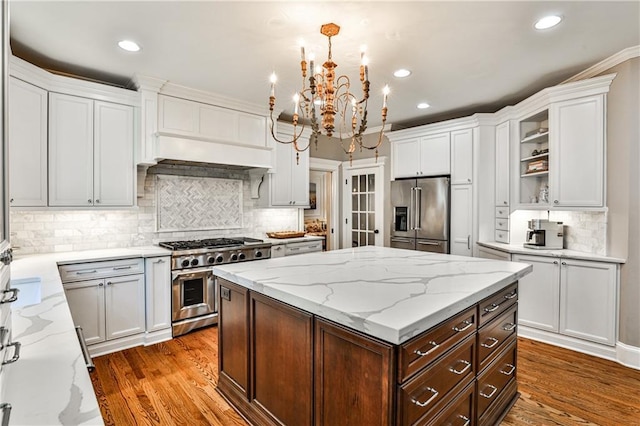 kitchen with a notable chandelier, high quality appliances, wood finished floors, and a kitchen island