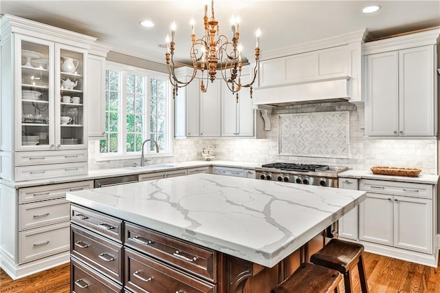 kitchen featuring light stone countertops, wood finished floors, a kitchen island, a sink, and a chandelier