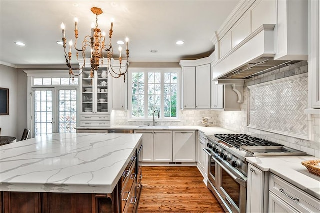 kitchen with custom range hood, ornamental molding, range with two ovens, french doors, and a sink