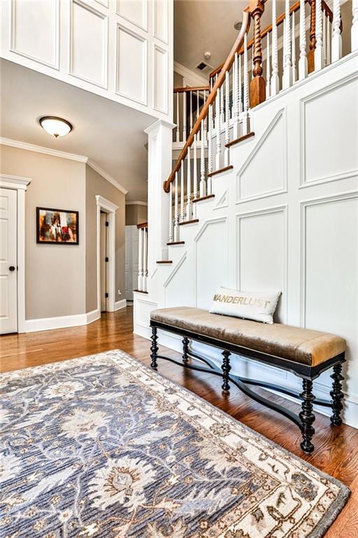 stairs with visible vents, crown molding, baseboards, and wood finished floors