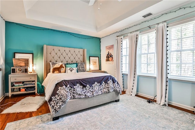 bedroom featuring visible vents, a raised ceiling, and multiple windows