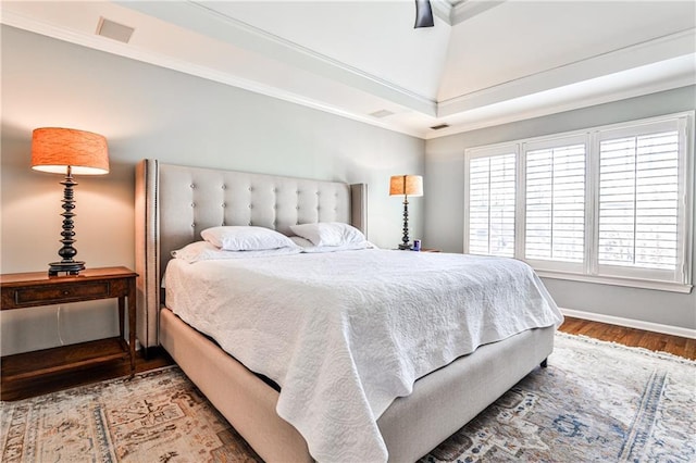 bedroom featuring crown molding, wood finished floors, visible vents, and baseboards