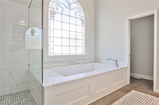 bathroom with baseboards, a bath, and a walk in shower