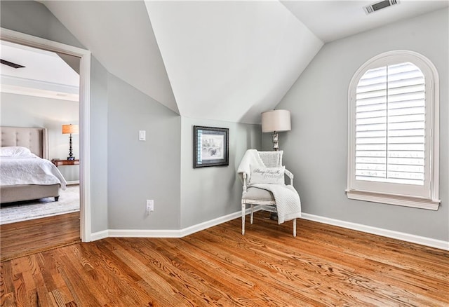 living area with visible vents, baseboards, lofted ceiling, and wood finished floors