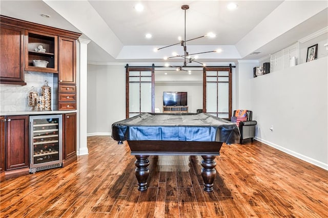 rec room with a tray ceiling, wine cooler, a barn door, and a dry bar