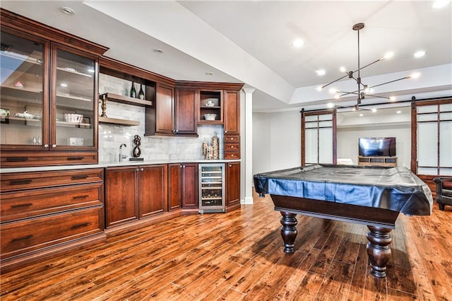 game room with beverage cooler, a barn door, indoor wet bar, wood finished floors, and a sink