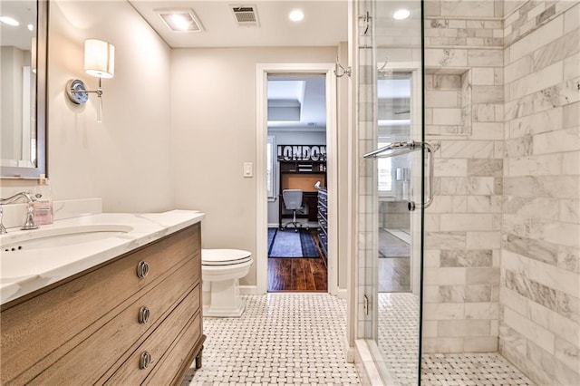 bathroom featuring visible vents, toilet, a stall shower, baseboards, and vanity