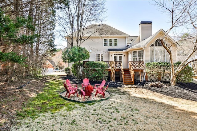 back of property featuring a wooden deck, an outdoor fire pit, a yard, a chimney, and stairs