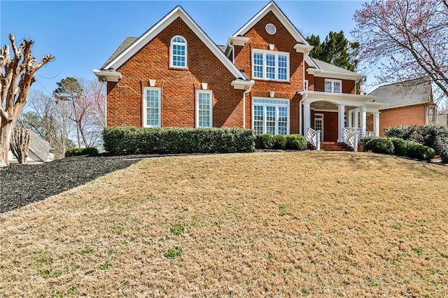 traditional-style home with brick siding and a front lawn