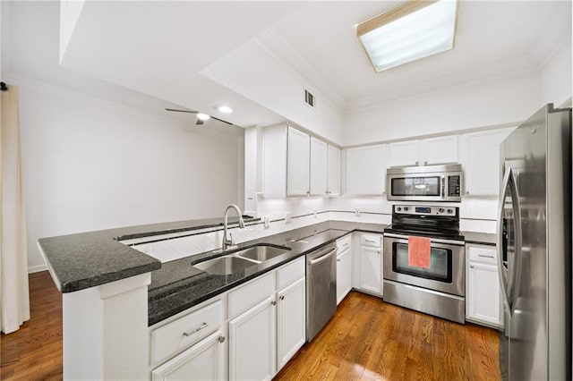 kitchen with stainless steel appliances, white cabinetry, sink, and kitchen peninsula