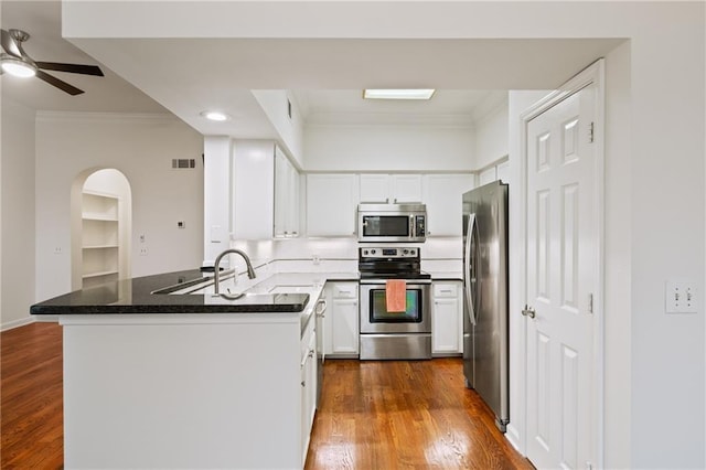 kitchen with ornamental molding, appliances with stainless steel finishes, white cabinets, and kitchen peninsula