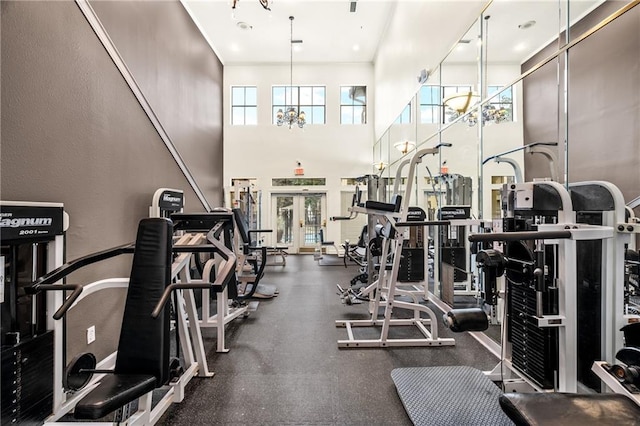 workout area featuring french doors, a high ceiling, and a notable chandelier