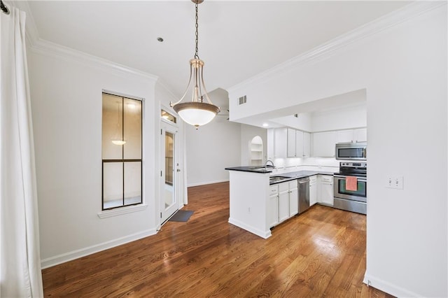 kitchen featuring wood-type flooring, appliances with stainless steel finishes, kitchen peninsula, pendant lighting, and white cabinets