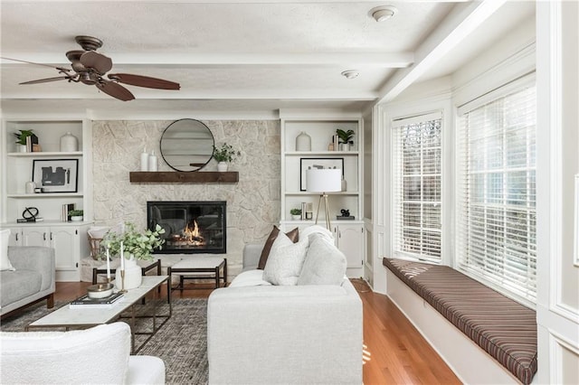 living room with hardwood / wood-style flooring, a fireplace, built in features, and beamed ceiling