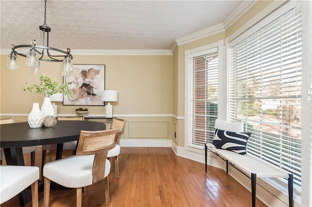 dining room featuring crown molding, wood-type flooring, and a textured ceiling