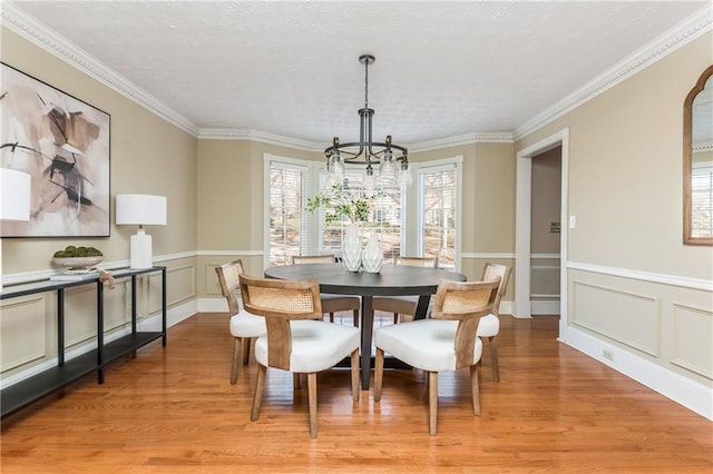 dining space featuring crown molding, light hardwood / wood-style flooring, and a notable chandelier