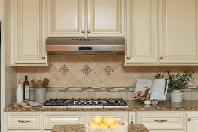 kitchen with dark stone countertops, stainless steel gas cooktop, and cream cabinetry