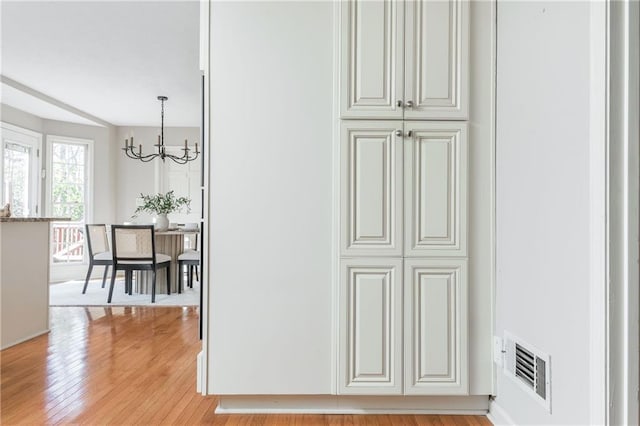 interior space featuring an inviting chandelier and light hardwood / wood-style flooring