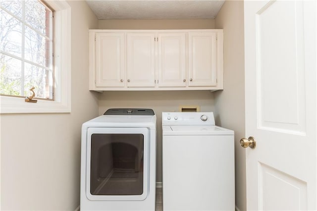 laundry area with cabinets, separate washer and dryer, and a textured ceiling