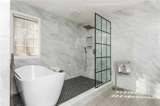 bathroom featuring separate shower and tub and tile walls