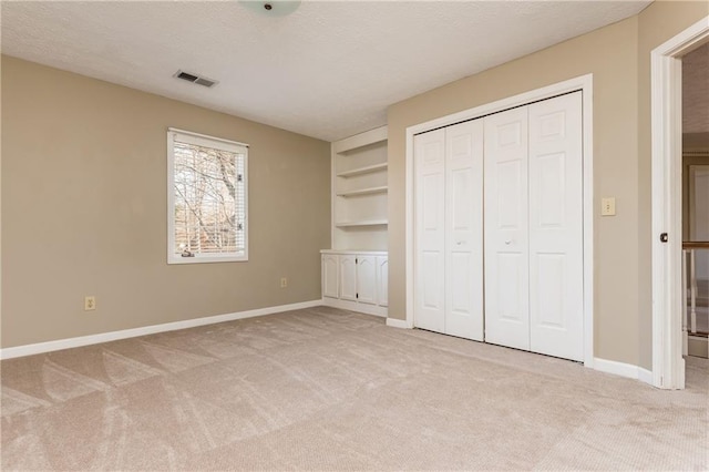 unfurnished bedroom featuring light colored carpet, a closet, and a textured ceiling