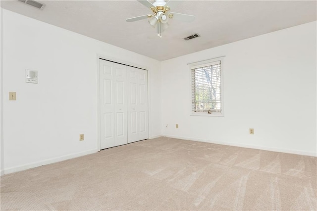 unfurnished bedroom with light colored carpet, ceiling fan, and a closet