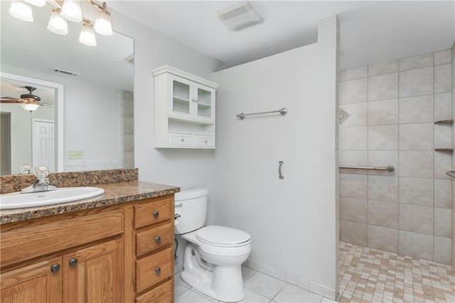 bathroom with toilet, a tile shower, vanity, ceiling fan, and tile patterned flooring