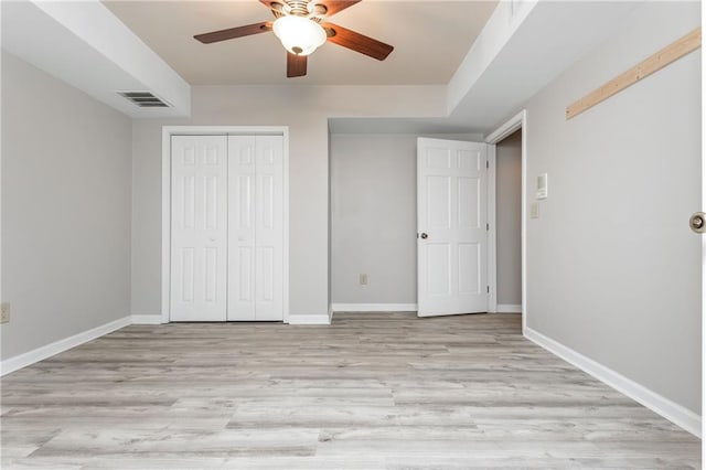 unfurnished bedroom featuring ceiling fan, a closet, and light wood-type flooring