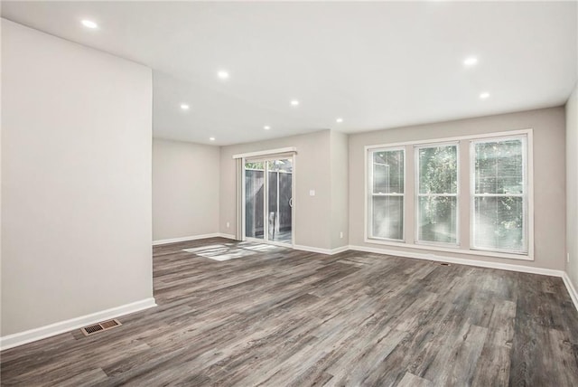 unfurnished room featuring dark wood-type flooring and a wealth of natural light