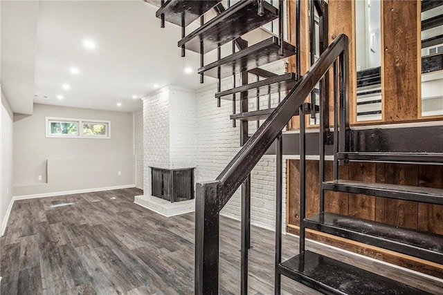 stairs with brick wall, a fireplace, and wood-type flooring