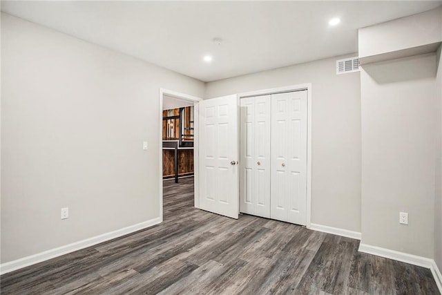 unfurnished bedroom featuring a closet and dark wood-type flooring