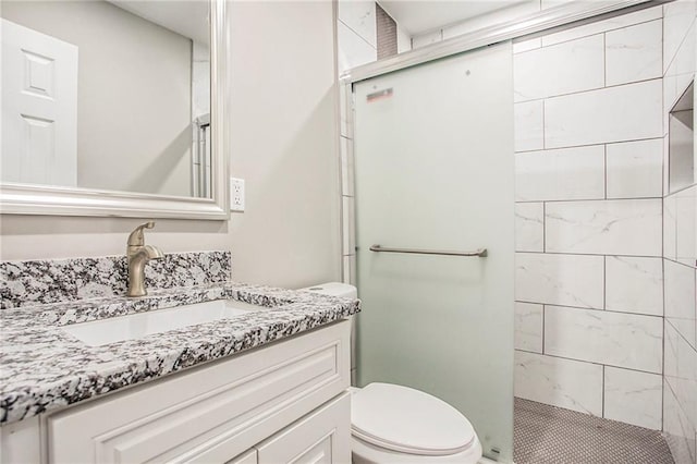 bathroom with vanity, a shower with shower door, and toilet