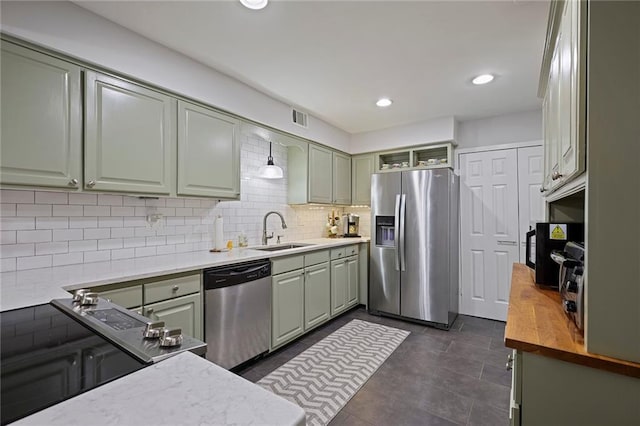 kitchen with wood counters, backsplash, green cabinets, sink, and appliances with stainless steel finishes