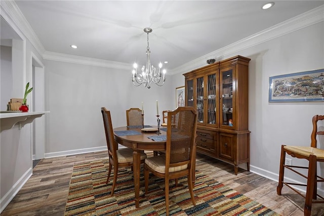 dining space featuring dark hardwood / wood-style flooring, an inviting chandelier, and crown molding