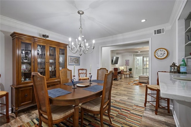 dining space with hardwood / wood-style flooring, crown molding, and a chandelier