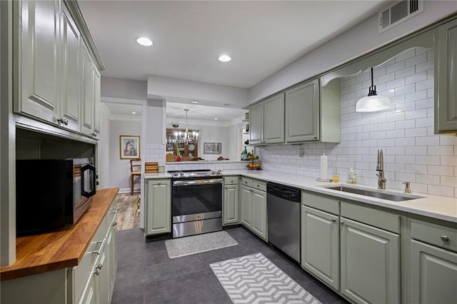 kitchen featuring sink, stainless steel appliances, crown molding, pendant lighting, and decorative backsplash