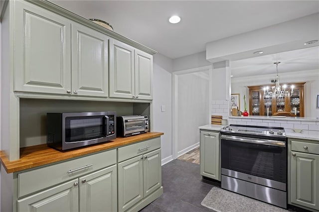 kitchen with wooden counters, dark tile patterned flooring, tasteful backsplash, decorative light fixtures, and stainless steel appliances