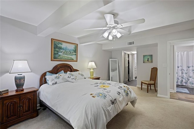 carpeted bedroom featuring beam ceiling, connected bathroom, and ceiling fan