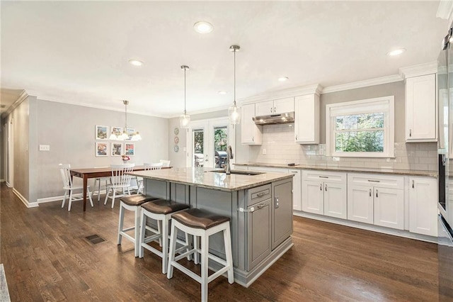 kitchen featuring dark wood finished floors, tasteful backsplash, a sink, and white cabinetry