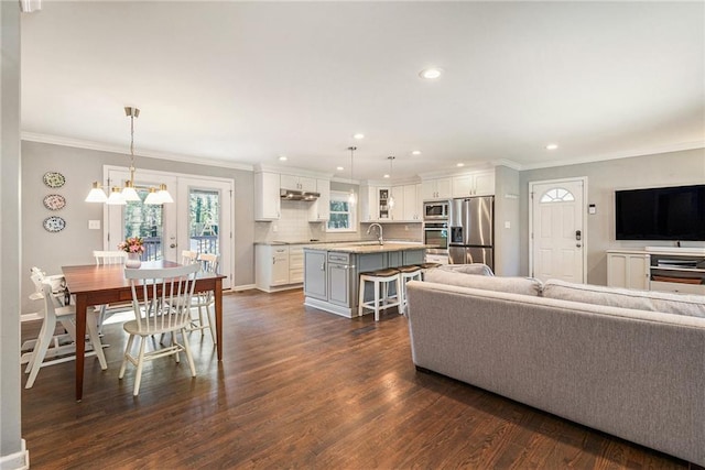 living room with recessed lighting, an inviting chandelier, dark wood-type flooring, ornamental molding, and baseboards