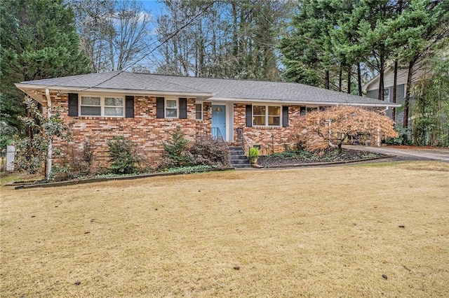 single story home with brick siding, a front yard, and a shingled roof