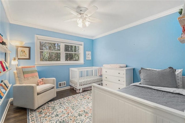 bedroom featuring ornamental molding, visible vents, baseboards, and wood finished floors