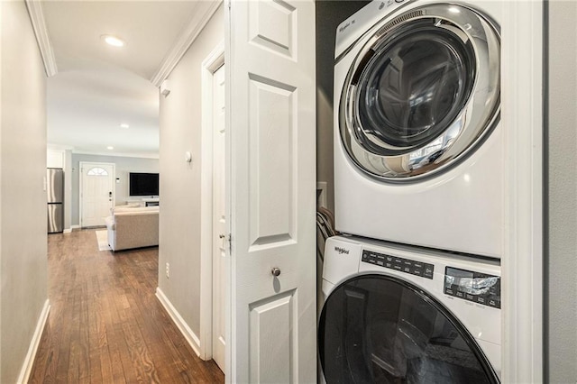 laundry room with laundry area, baseboards, dark wood finished floors, stacked washer and clothes dryer, and crown molding