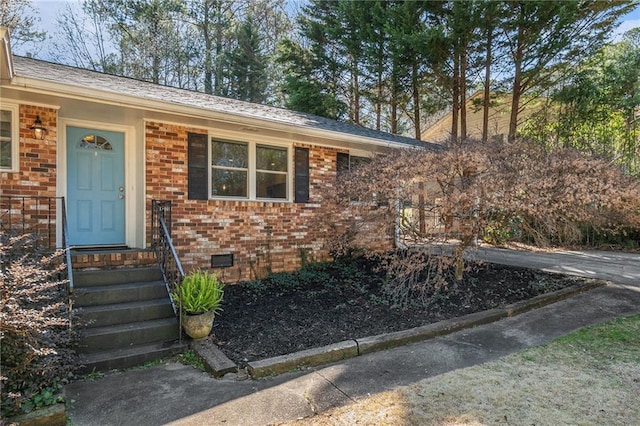 property entrance with a shingled roof, crawl space, and brick siding