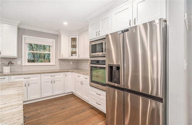 kitchen with dark wood-style flooring, appliances with stainless steel finishes, white cabinets, and backsplash