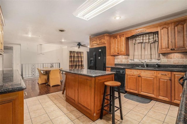 kitchen featuring ceiling fan, a center island, sink, light tile patterned flooring, and black appliances