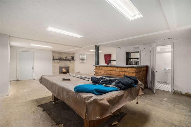 rec room with pool table, concrete floors, and a brick fireplace